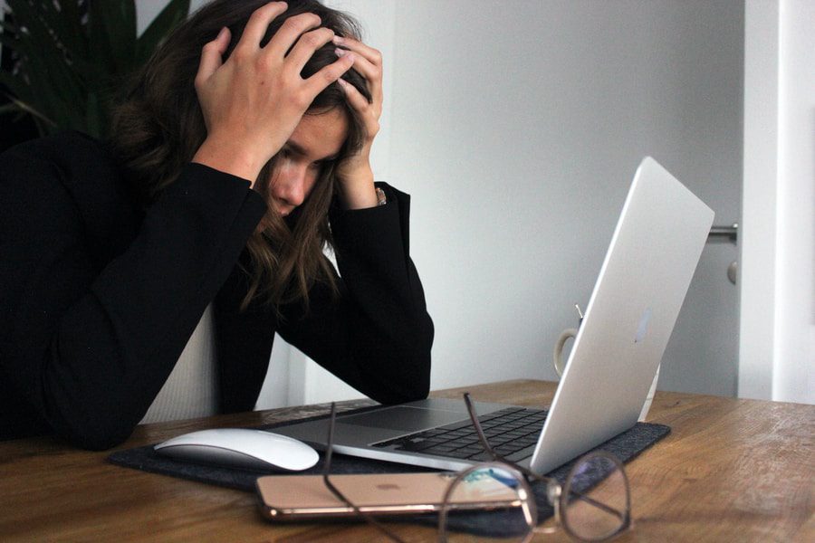 woman in black long sleeve shirt covering her face with her hands listening to podcast