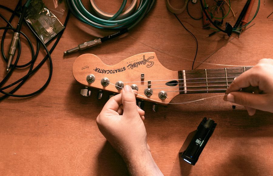 person tuning brown electric guitar