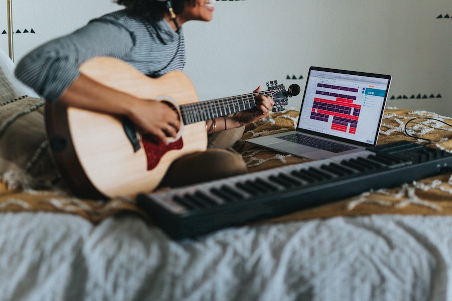 man in gray t-shirt playing acoustic guitar with audio interface