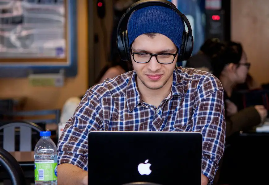 man using MacBook with studio headphones